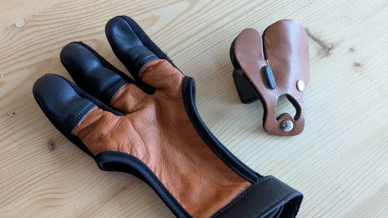 Schießhandschuh und Fingertab aus Leder auf einem Tisch